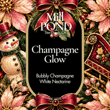 Load image into Gallery viewer, A festive decorative label design for Mill Pond Soap, featuring the scent name 'Champagne Glow' in white text on a black central panel, surrounded by pink poinsettias, red ribbons, green foliage, a snowman, and a gold ornament.
