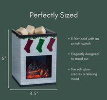 Load image into Gallery viewer, Small white brick fireplace‑style wax warmer with three holiday stockings on the front and a glowing LED fire inside. Cream wax cubes sit on top. The warmer is shown with size labels and brief feature text beside it.
